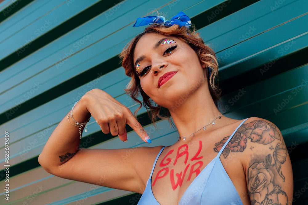 Woman with 'GAL PWR' painted on her arm against a blue background