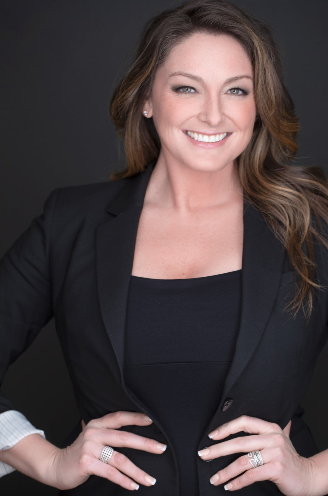 A women in a business suit smiling with hands on her hips- Carrie H