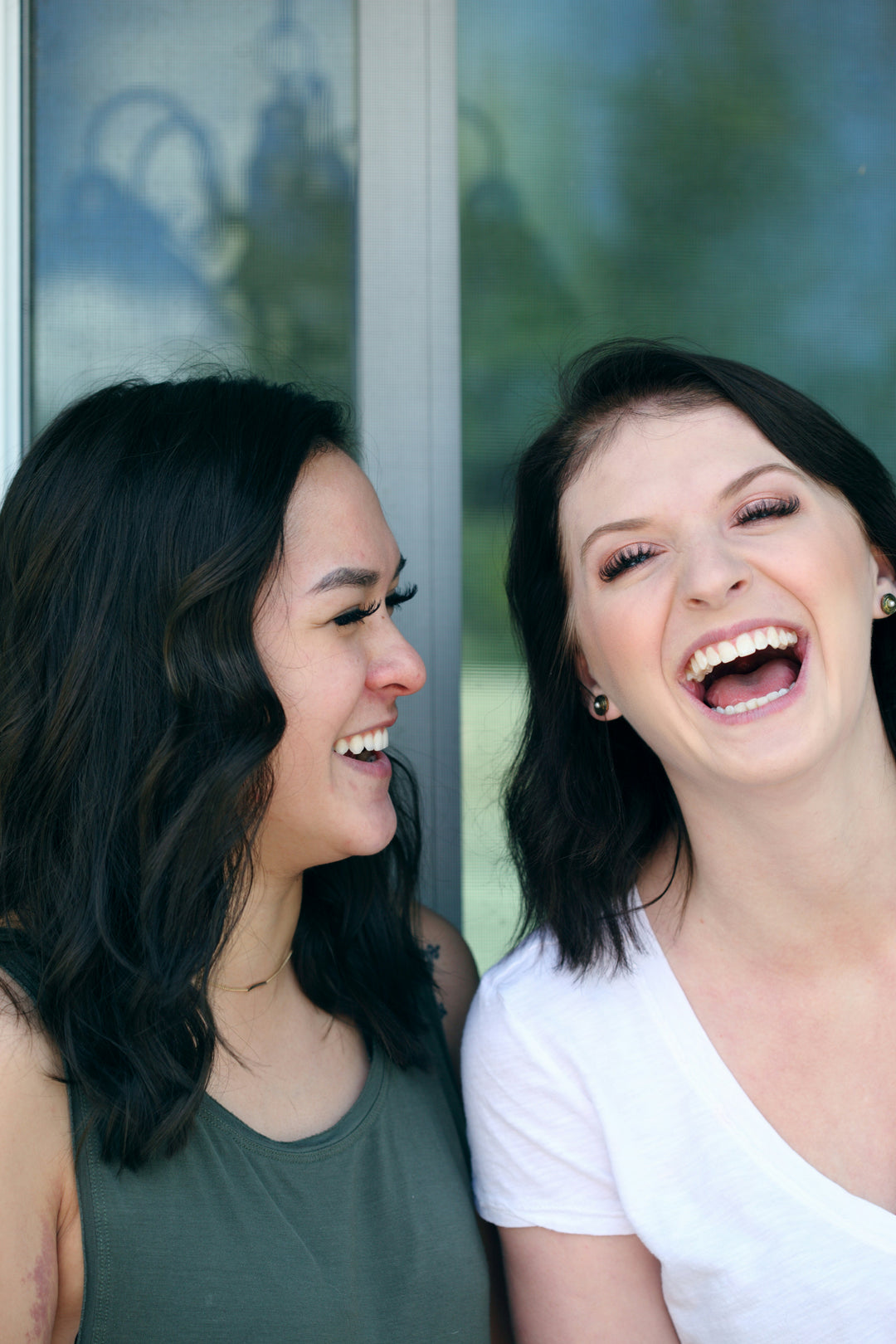 Two women with long brown hair laughing