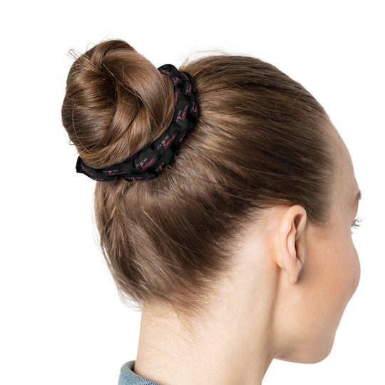 A black scrunchie with pink text all-over print, on a white background.