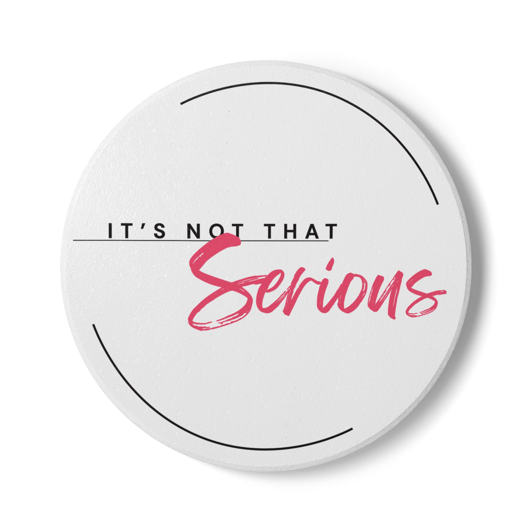 Round ceramic coaster with black and pink text that reads 'IT'S NOT THAT Serious' on a white background with a non-slip cork backing.
