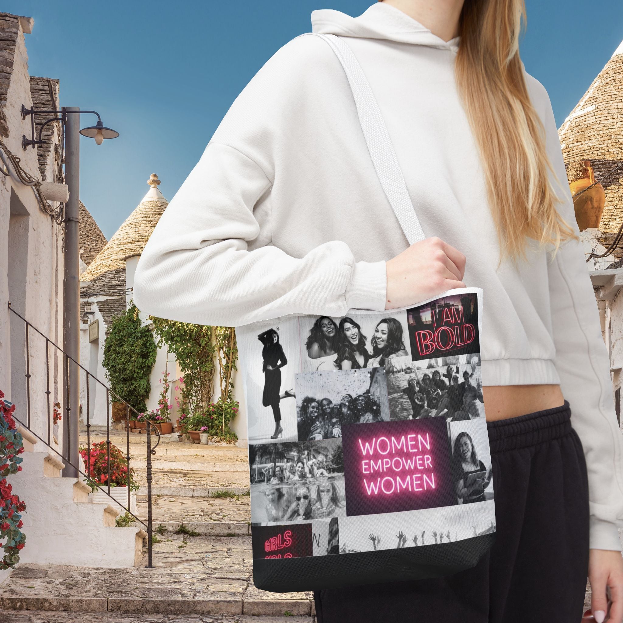 A person wearing a white hoodie is holding a black tote bag with a bold design featuring text and various images related to women's empowerment.