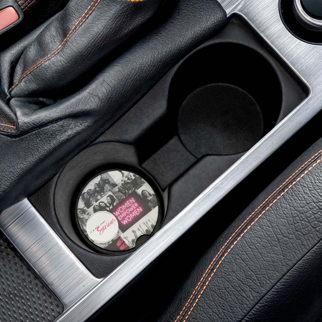 Car cup holder with a decorative coaster featuring a feminist design.