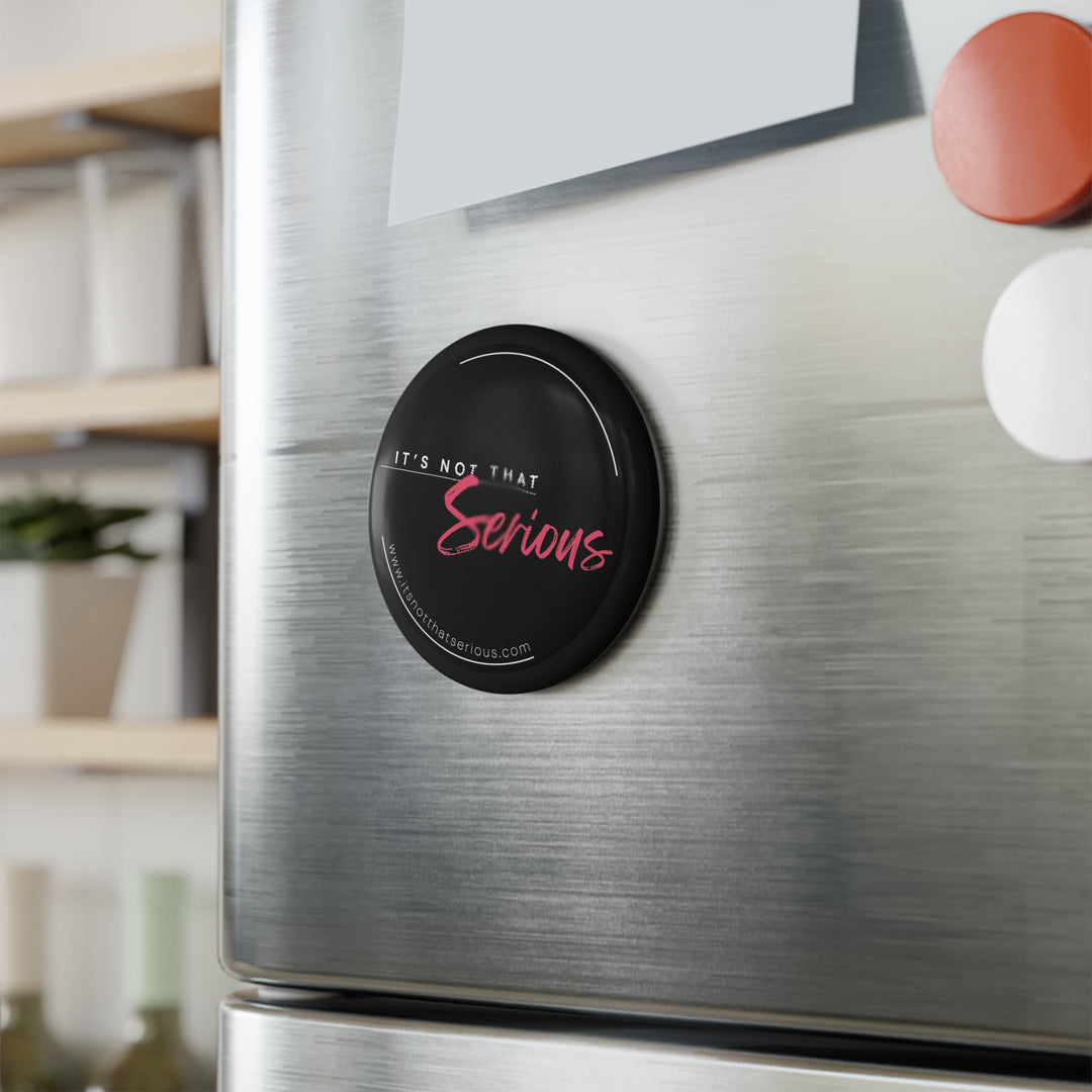 A round black button magnet with the text 'It's not that serious' in pink, attached to a refrigerator.