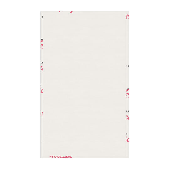 A white cotton tea towel with red text pattern hanging on a white shelf, with kitchen items and a plant in the background.