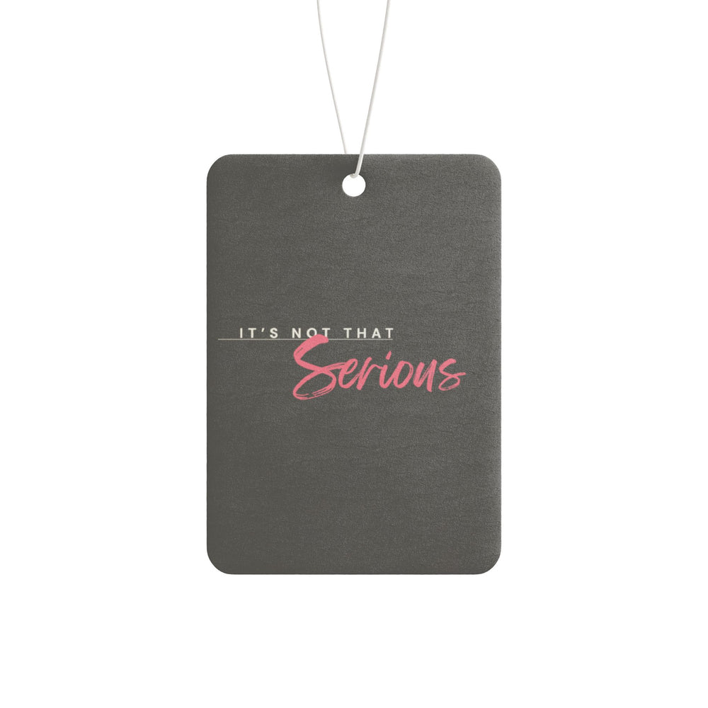 A gray car air freshener with pink text that reads 'It's Not That Serious' hanging by a white string.
