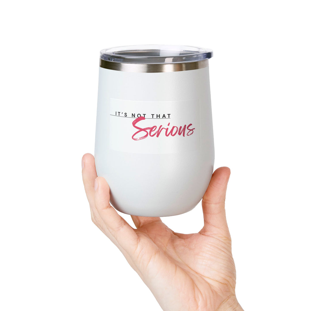 A hand holding a white 12oz wine tumbler with a printed phrase 'It's Not That Serious' on the side,