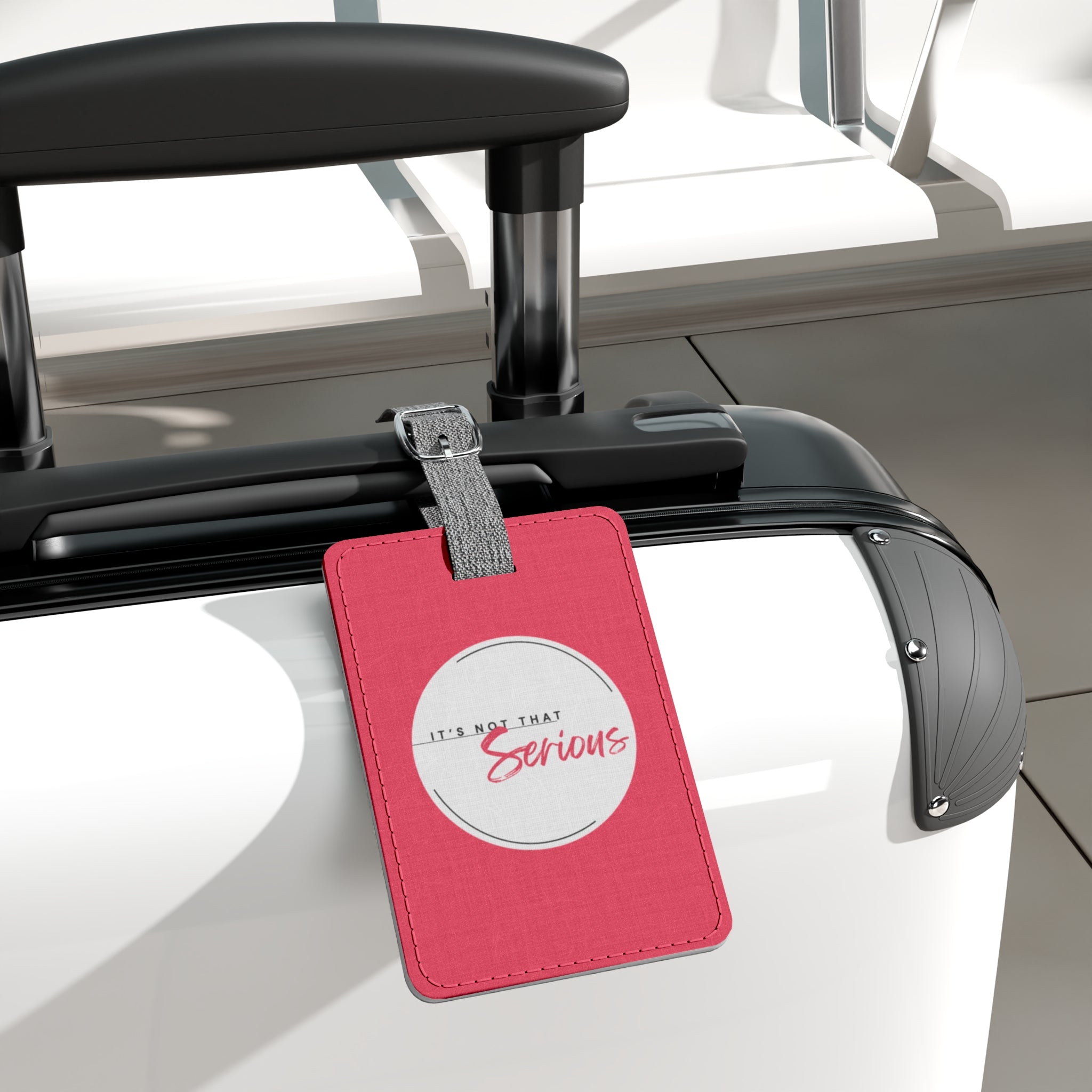 Pink luggage tag with 'It's Not That Serious' text attached to a car roof rack.