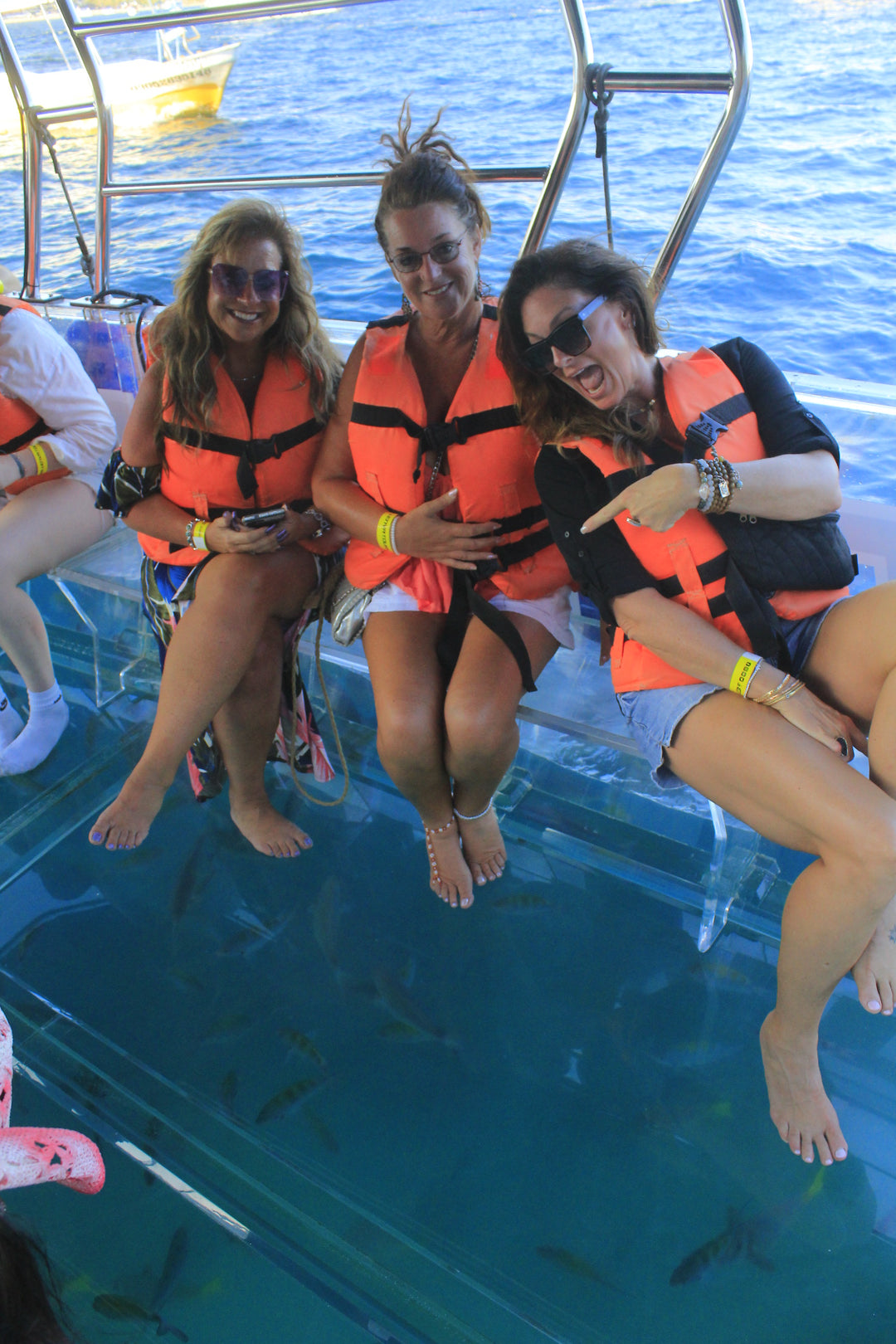 Three women in a see through bottom boat looking at fish
